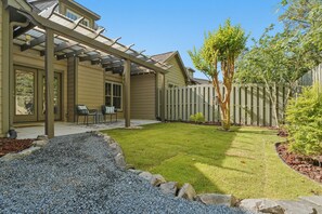 A backyard with a pergola, a patio with chairs, a lawn, and a wooden fence. - Cypress Blue - Turo Rental Available (Southern Pines)