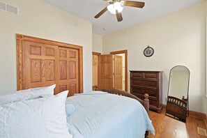 Ein Schlafzimmer mit einem Bett, einem Schminktisch, einem Spiegel und einem Deckenventilator.