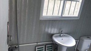 A small bathroom with a shower, sink, and window. - SJD Sagana Resort (Macarthur)