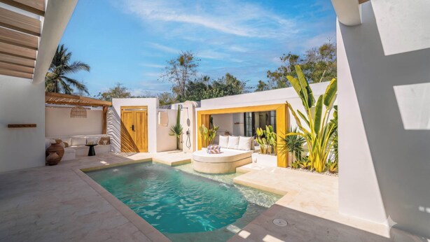 Un área de piscina moderna al aire libre con una zona de estar integrada y una puerta de madera.