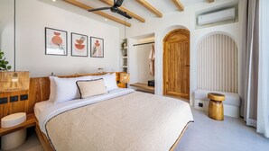 Un dormitorio moderno con una cama grande, vigas de madera, ventilador de techo y cuadros en la pared.