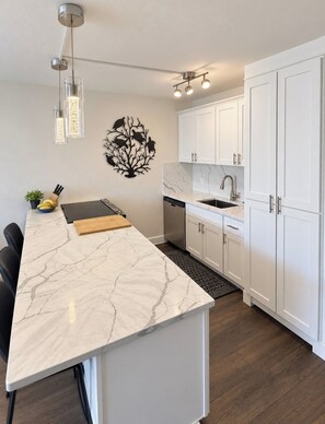 A modern kitchen with white cabinetry, a marble countertop, and pendant lighting. - “Kīhei Hideaway” @Maui Vista, 30 Sec the Beach, Ground Floor, King Bed & AC (Kihei)