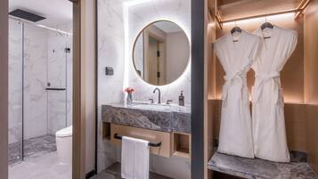 Un baño moderno con lavamanos de mármol, un espejo grande, cabina de ducha y un perchero para batas.