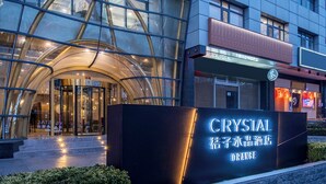 A modern building with a glass facade, a prominent sign for 'CRYSTAL ORANGE THEATER', and a well-lit entrance. - Crystal Hotel  Beijing Guomao Heshenghui (Beijing)
