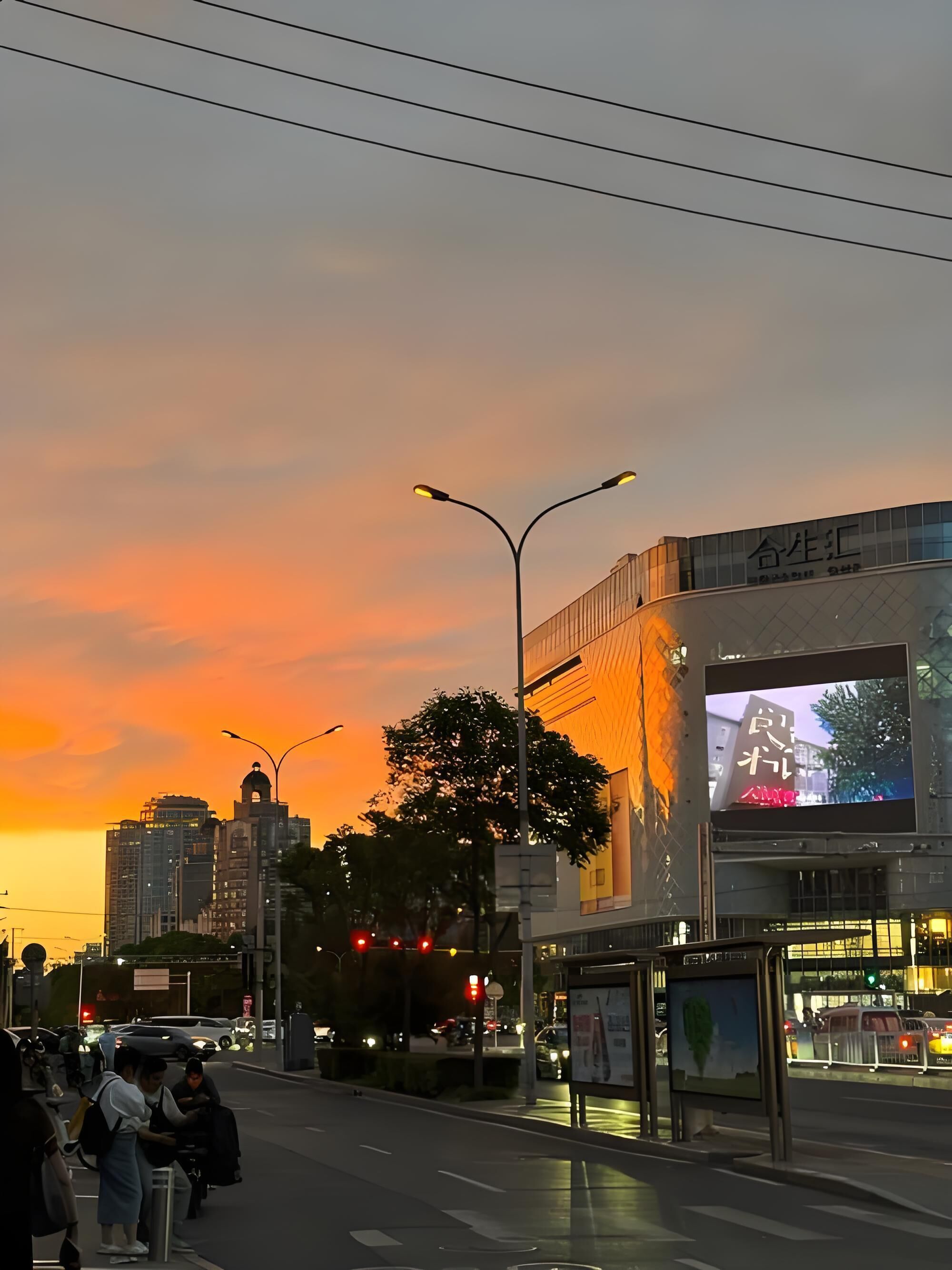 Une vue d’une ville au crépuscule, avec un bâtiment sur lequel est installé un grand panneau d’affichage numérique.