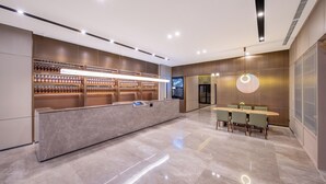 A modern hotel lobby with a reception desk, a digital information board, and a dining area with a round table and chairs. - Crystal Hotel  Beijing Guomao Heshenghui (Beijing)