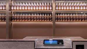 A digital kiosk with a screen displaying information, located in a room with a marble floor and a wall of neatly arranged liquor bottles. - Crystal Hotel  Beijing Guomao Heshenghui (Beijing)