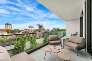 Ein Balkon mit einer Couch, zwei Stühlen und einem kleinen Tisch.