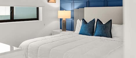 Une chambre d’hôtel moderne avec un grand lit, une table de chevet, une lampe et une fenêtre.