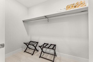 A minimalist bathroom with a white wall, a towel rack with folded towels, and two metal towel racks. - Beautiful Melbourne Beach Retreat | Pool, Hot Tub & Private Balcony 🌴 (Melbourne Beach)