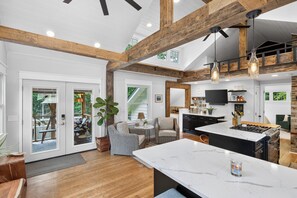 A spacious kitchen with a large island, wooden beams, and pendant lighting. - Charming Lake Minnetonka Cottage with Barrel Sauna (Spring Park)