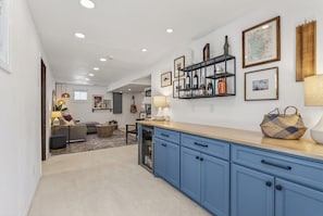 A modern kitchen with blue cabinets, a wooden countertop, and a wine rack.