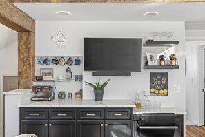 A modern kitchen with a flat-screen TV, a coffee machine, and various kitchenware.
