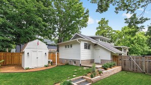 A residential property with a well-maintained lawn, a wooden deck, and a small shed.