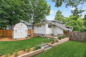 A residential property with a well-maintained lawn, a wooden deck, and a small shed.