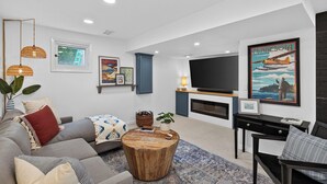 A modern living room with a sofa, coffee table, and a flat-screen TV mounted on the wall.