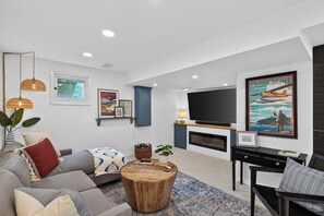 A modern living room with a sofa, coffee table, and a flat-screen TV mounted on the wall.