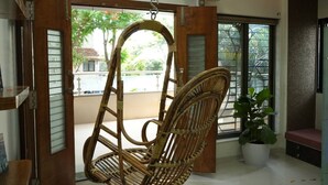 A room with a wooden swing chair, a potted plant, and a fan.