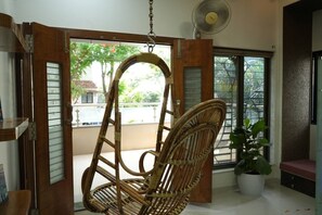A room with a wooden swing chair, a potted plant, and a fan.