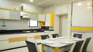 A modern kitchen with a dining area, featuring a central island, cabinets, and a window.