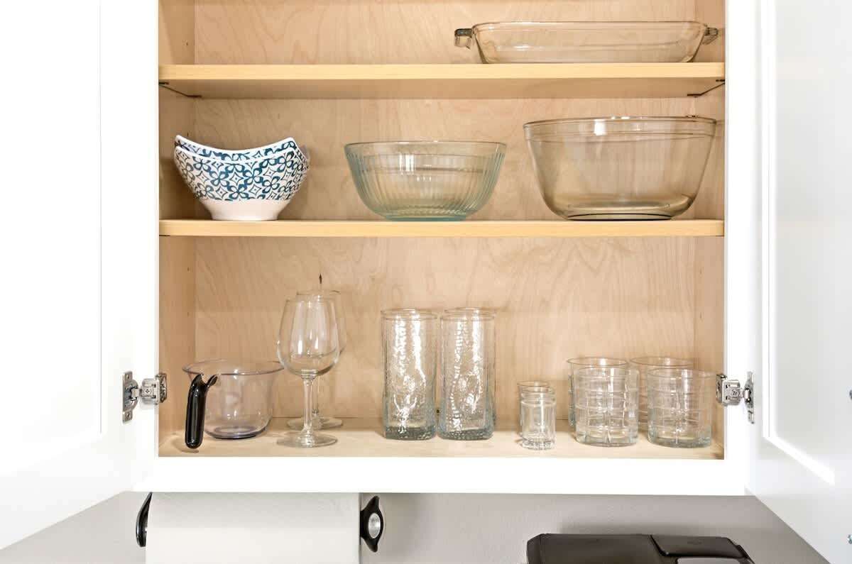 Un meuble de cuisine avec des étagères contenant divers objets en verre et des bols.