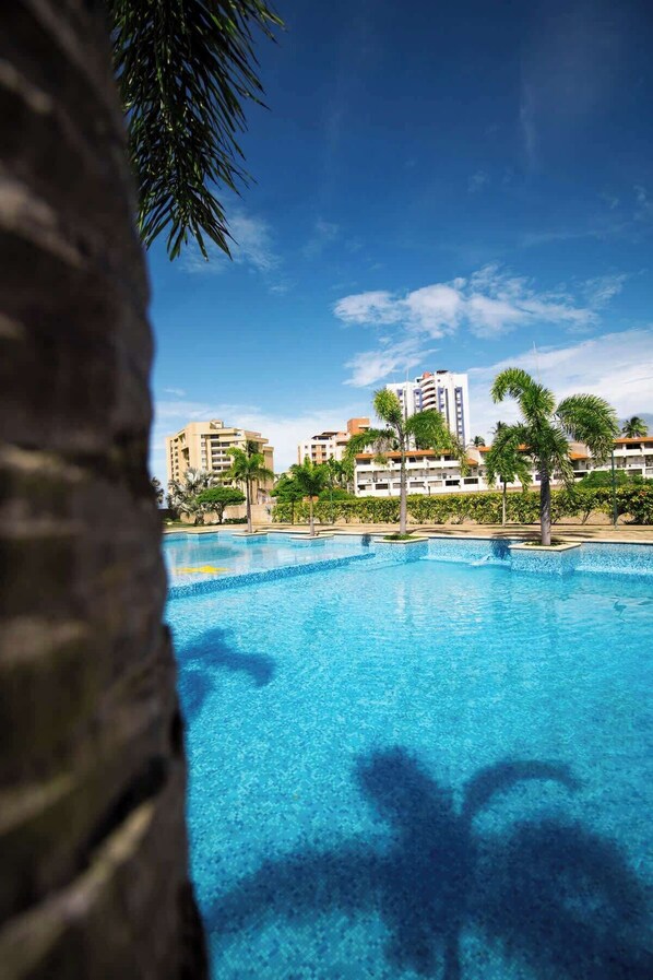 A clear blue swimming pool with a view of a multi-story building in the background.