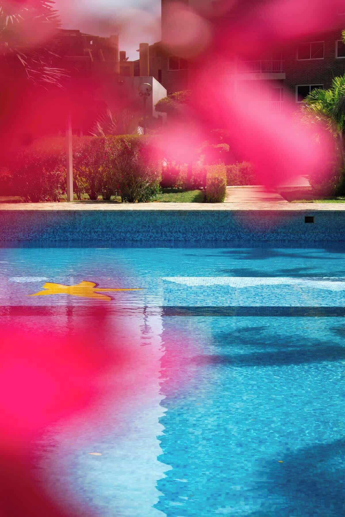 Una piscina con acqua cristallina, circondata dal verde e con un edificio sullo sfondo.