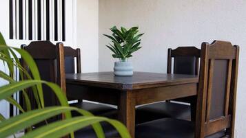 A dining table with chairs, a potted plant, and a window with vertical blinds.