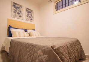 Ein Schlafzimmer mit einem Bett, einem Kopfteil und zwei an der Wand befestigten Bildern.