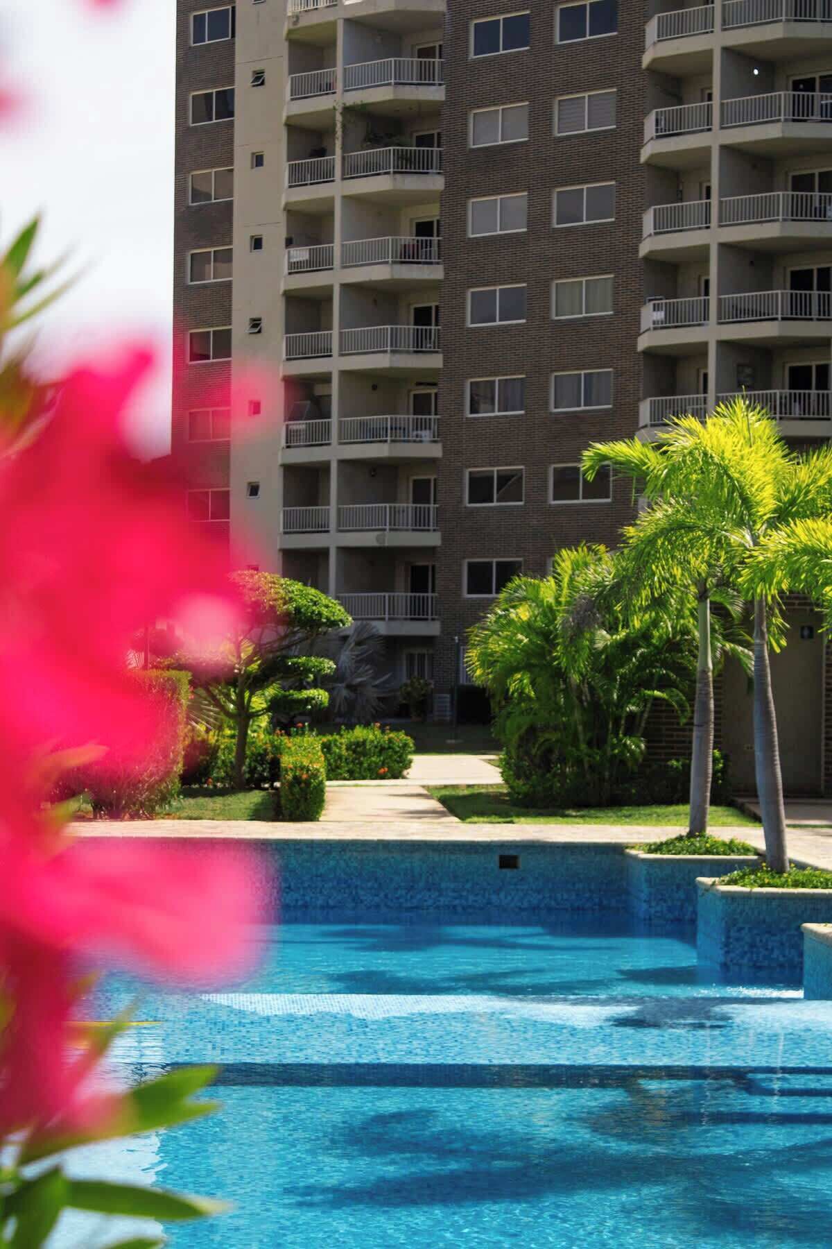 A multi-story residential building with balconies, a swimming pool, and well-maintained landscaping.
