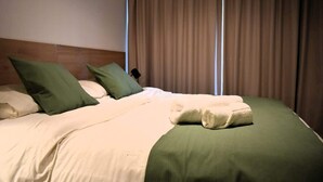 Ein Hotelzimmer mit Bett, Kissen, Decke und Vorhängen.