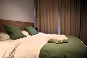 Ein Hotelzimmer mit Bett, Kissen, Decke und Vorhängen.