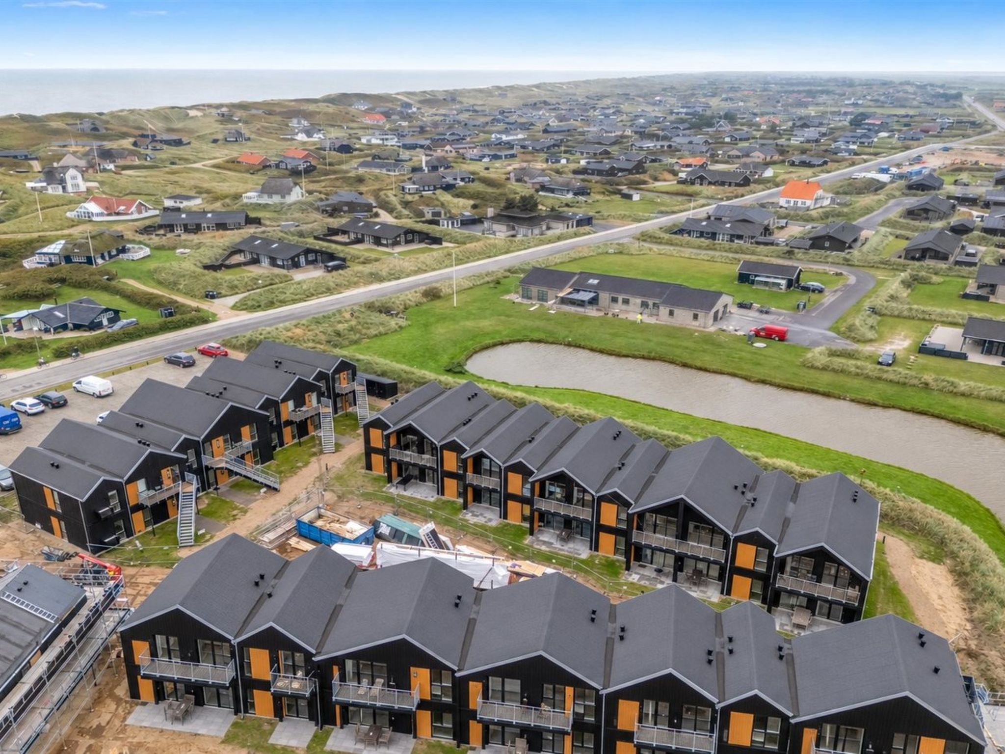 Un quartier résidentiel avec des maisons modernes, une route et un plan d’eau.