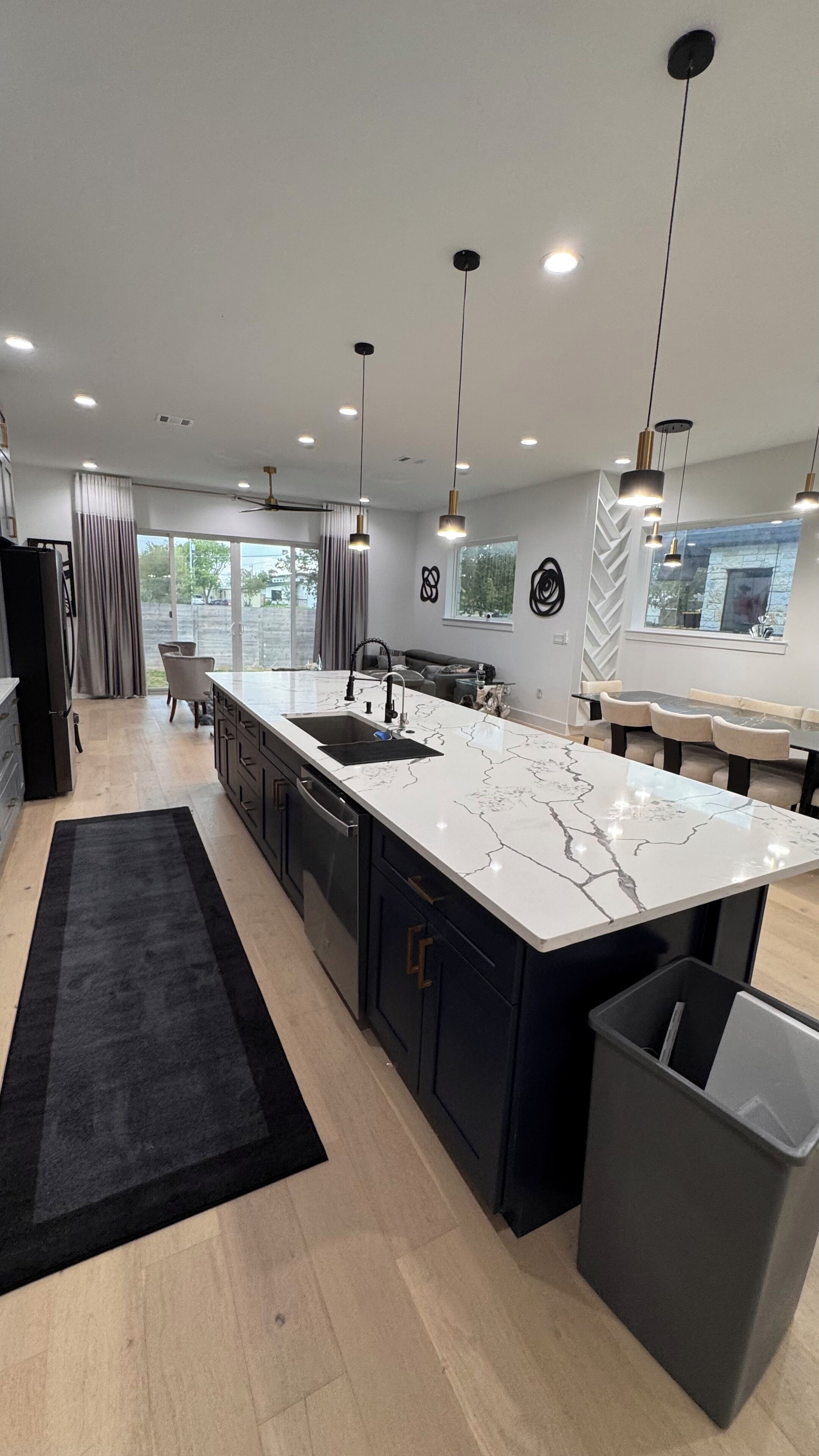 A modern kitchen with a central island, pendant lighting, and a view to the outdoors.