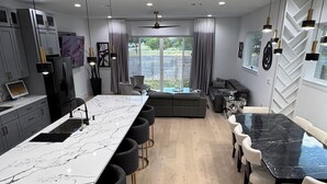 Ett modernt kök med en bänkskiva i marmor, en matplats med ett bord i svart marmor och en sittgrupp med soffor och stolar.