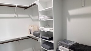 Ett förråd med vita hyllor, en träbänk och en väska på golvet.