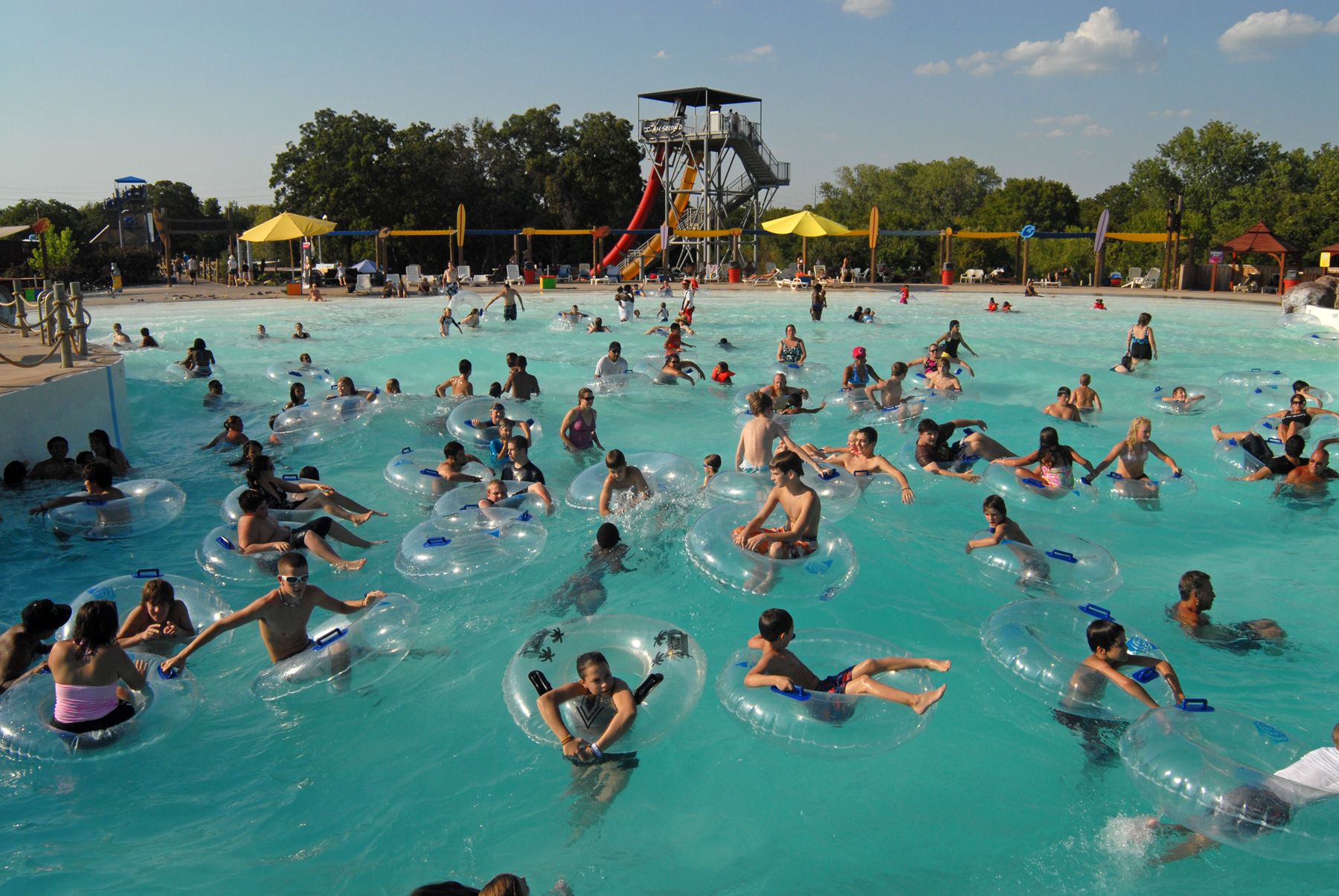 A large outdoor swimming pool with people floating on inner tubes.