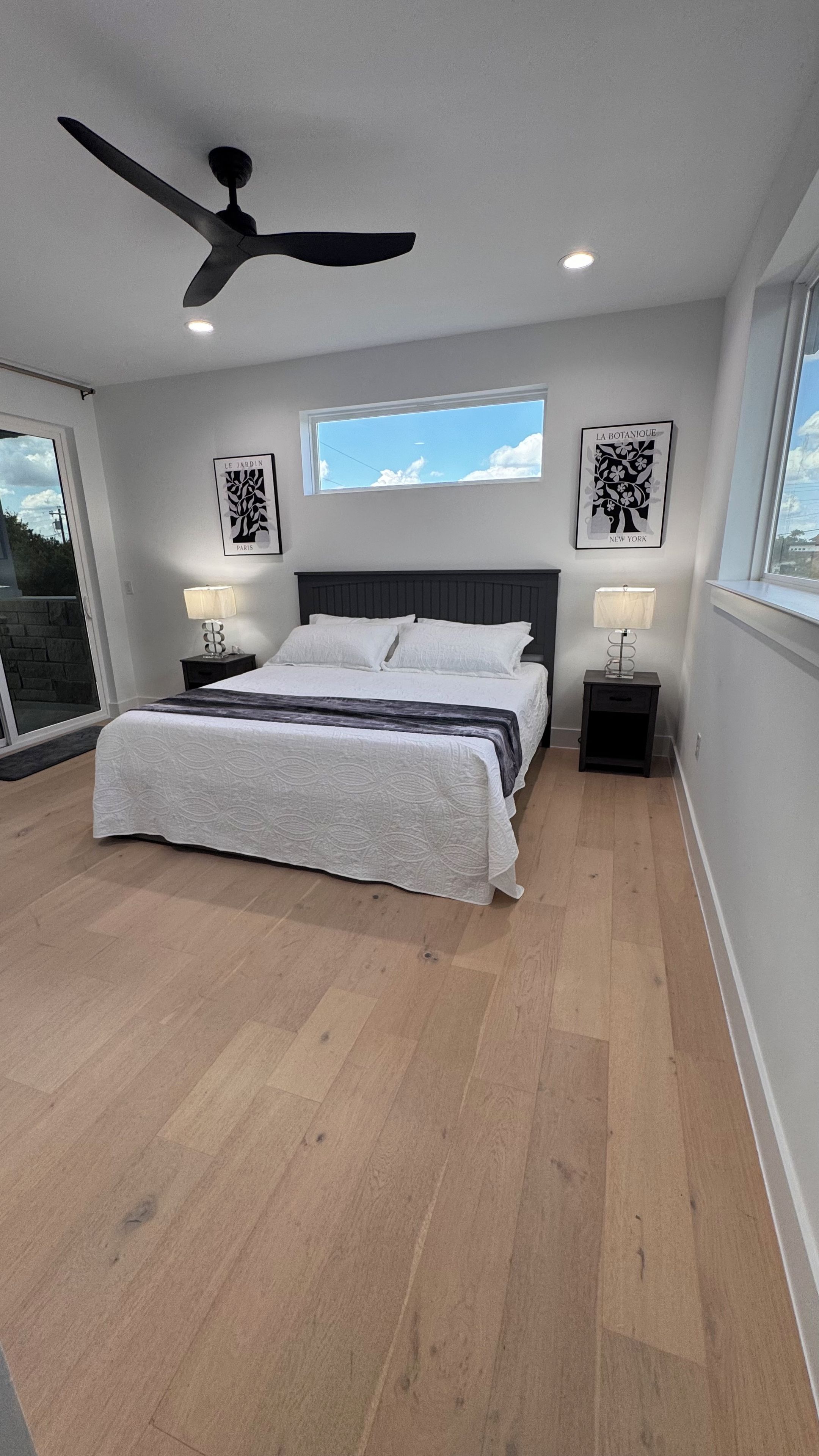 A modern bedroom with a large bed, a ceiling fan, and two bedside tables with lamps.