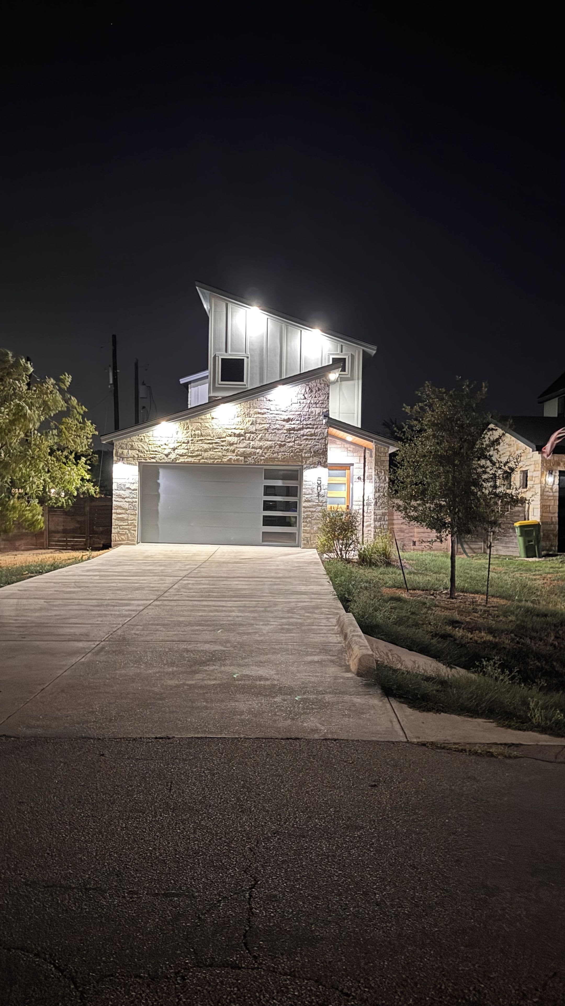 A modern house with a garage, stone facade, and a driveway leading to the entrance.