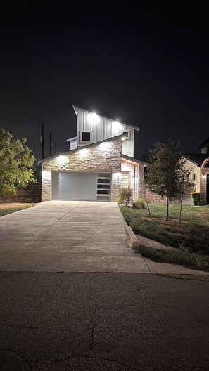 Une maison moderne dotée d’un garage, d’une façade en pierre et d’une allée menant à l’entrée.