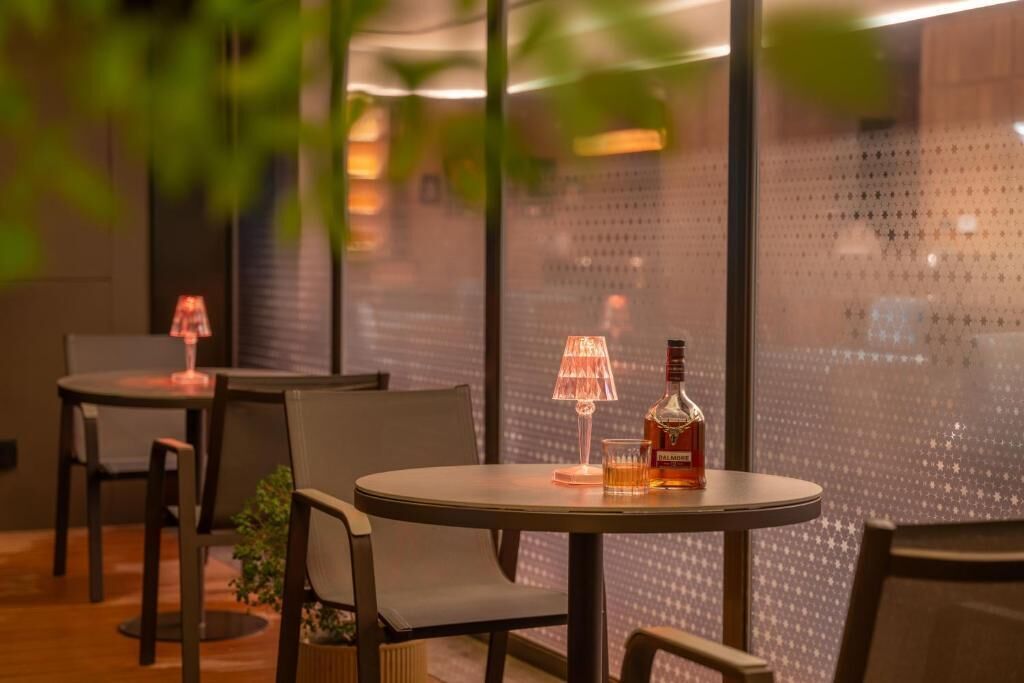 A cozy indoor seating area with round tables, chairs, and a bottle of liquor.