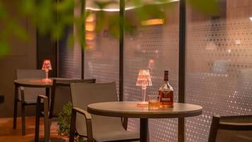 A cozy indoor seating area with round tables, chairs, and a bottle of liquor.