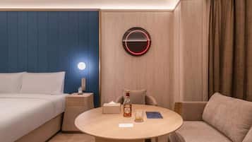 A hotel room with a bed, a round table with a bottle, a glass, and a book.