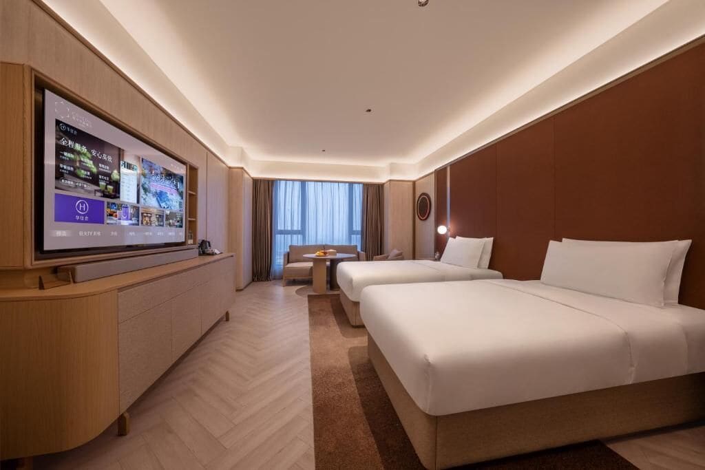 Habitación de hotel con una televisión de pantalla plana grande, un sofá, dos camas y vistas al exterior.