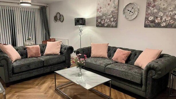 Ein Wohnzimmer mit zwei Sofas, einem Couchtisch, einer Stehlampe und Wandbildern.