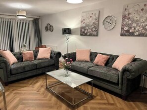 Ein Wohnzimmer mit zwei Sofas, einem Couchtisch, einer Stehlampe und Wandbildern.