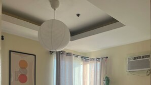 Ein Schlafzimmer mit einem Bett, einer Deckenleuchte, einer Wand-Klimaanlage und einem gerahmten Bild.