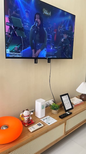 A television mounted on a wall displaying a live concert. - JFS Cozy 1-bedroom Staycation in beautiful Manila - Near US Embassy (Manila)