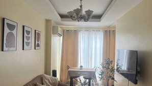 Ein Wohnzimmer mit einer Couch, einem Esstisch und einem an der Wand befestigten Fernseher.