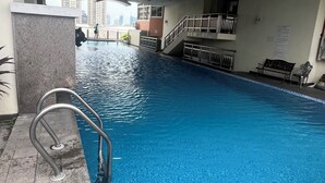Ein Hallenbad mit glatter, blauer Wasseroberfläche, einer Metallleiter und einer gewölbten Decke.